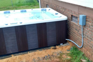 hot tub in backyard of red brick house