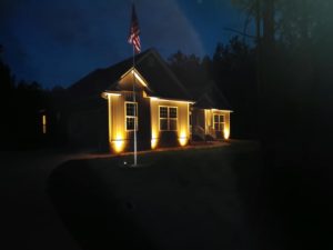 Suburban home lit with landscape lights at night