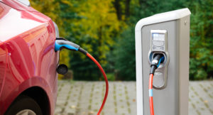 residential electric vehicle charger plugged into red car in driveway