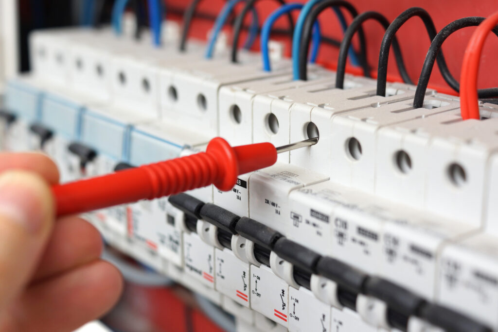 Hand of an electrician inspecting a circuit breaker & panel 