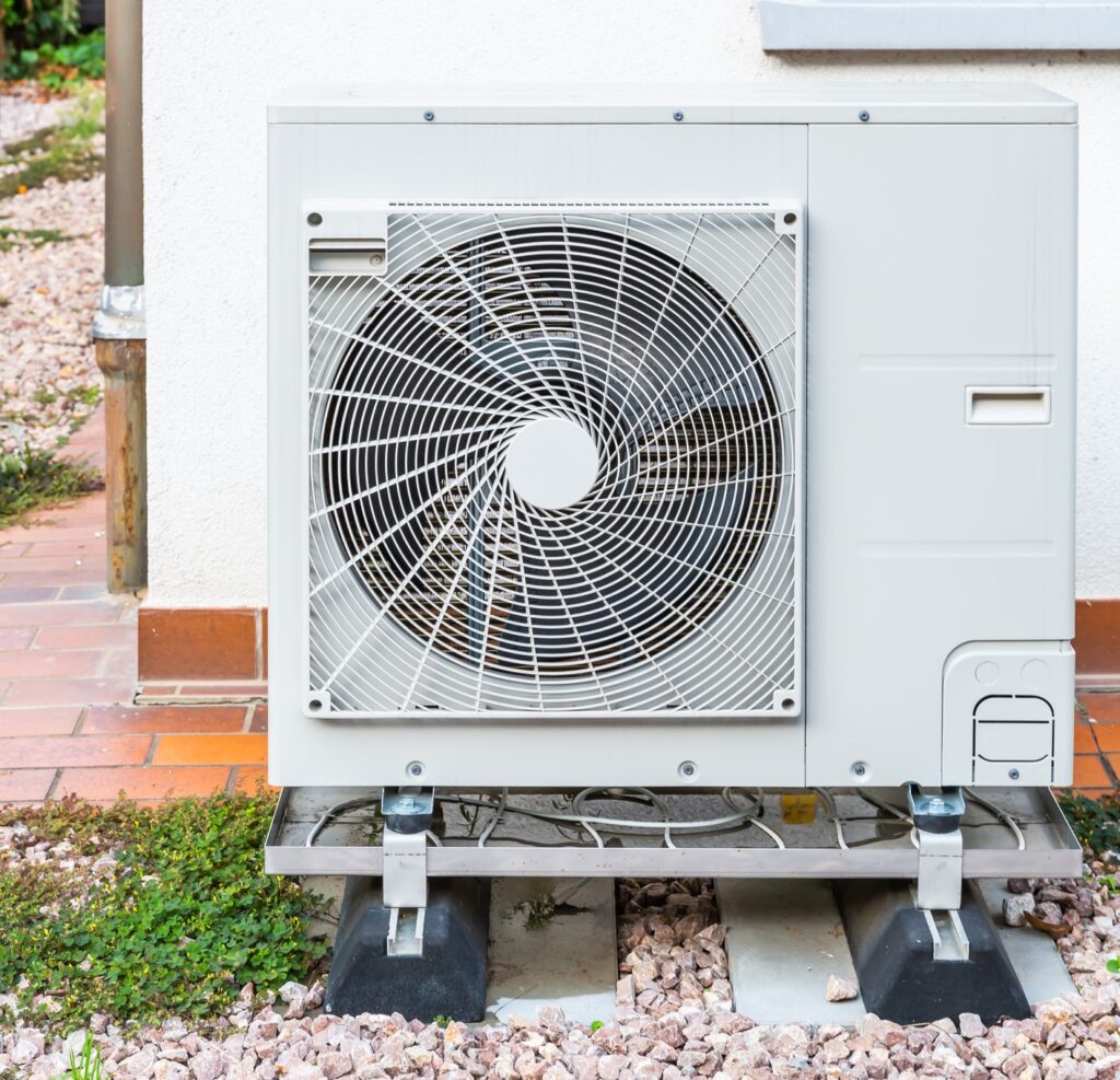 Newly installed heat pump on a concrete pad against a house's exterior wall